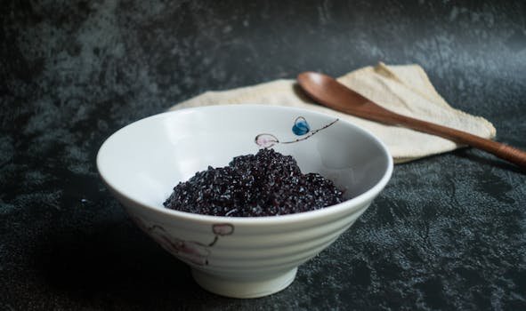 Close-up of a bowl filled with delicious black rice on a textured surface.