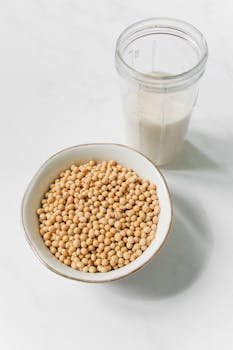 A bowl of soybeans and a glass of soy milk on a white background, ideal for health and nutrition themes.