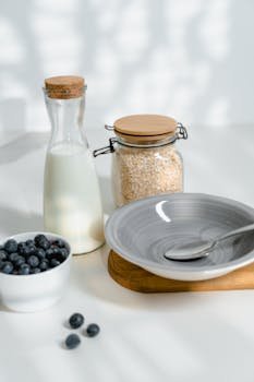 A clean breakfast scene with blueberries, milk, and oats.
